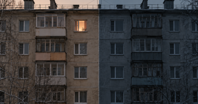 Многоэтажный дом, разделённый пополам: слева светится одно окно, справа фасад в холодной тени