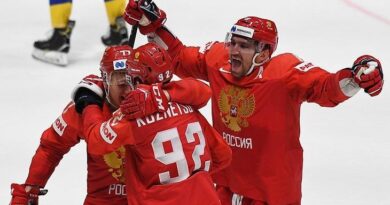 Игроки сборной России в красной форме обнимаются на льду