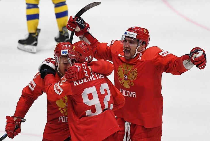 Игроки сборной России в красной форме обнимаются на льду