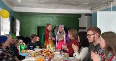 Молодёжь и женщины в национальных костюмах за накрытым столом на встрече «Шунды»
